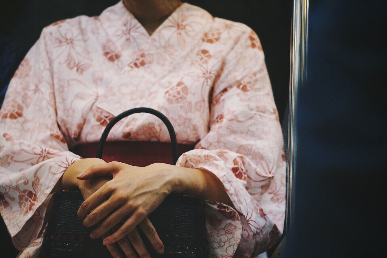 Midsection of woman in woman in traditional clothing holding purse