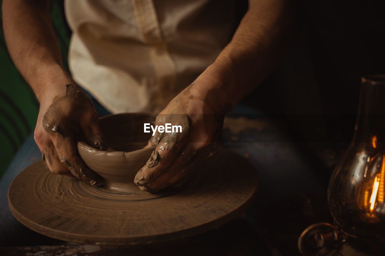 potter's wheel, art, craft, pottery, occupation, skill, making, one person, hand, clay, working, spinning, craftsperson, creativity, adult, expertise, molding a shape, earthenware, ceramic, indoors, workshop, wheel, motion, heat, holding, men, midsection, close-up