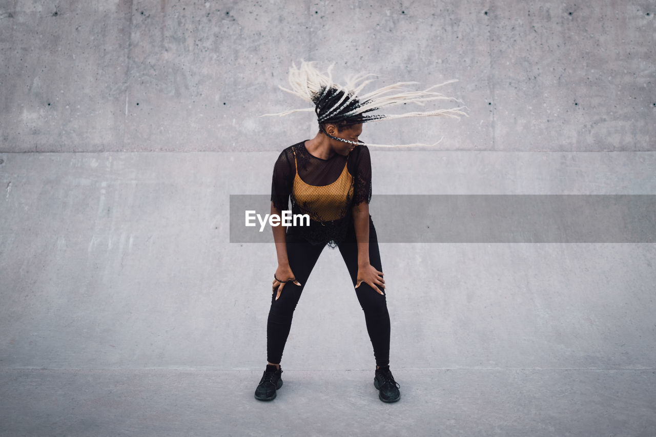 Full length of teenage girl with tousled hair dancing at skateboard park