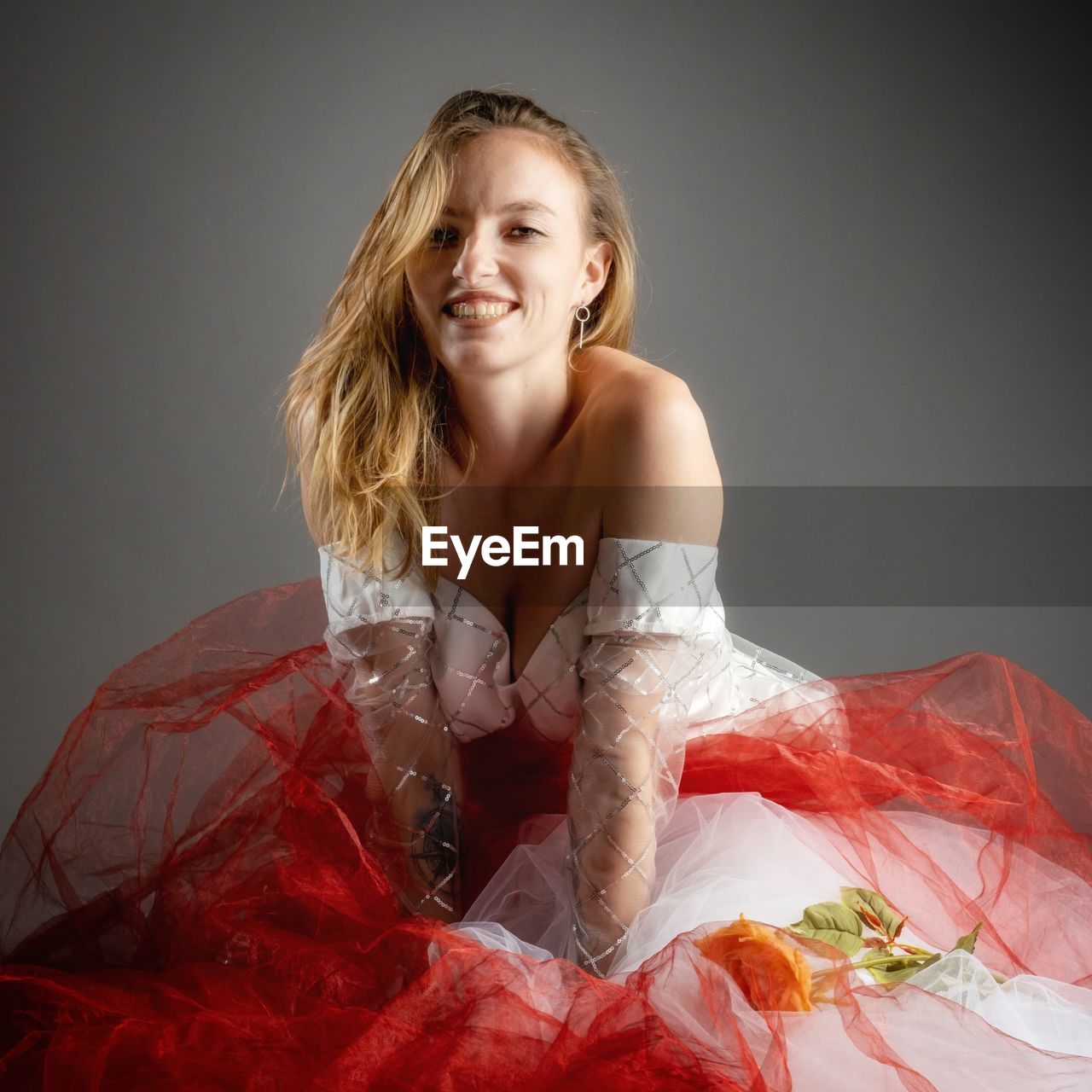 Portrait of young woman standing against gray background