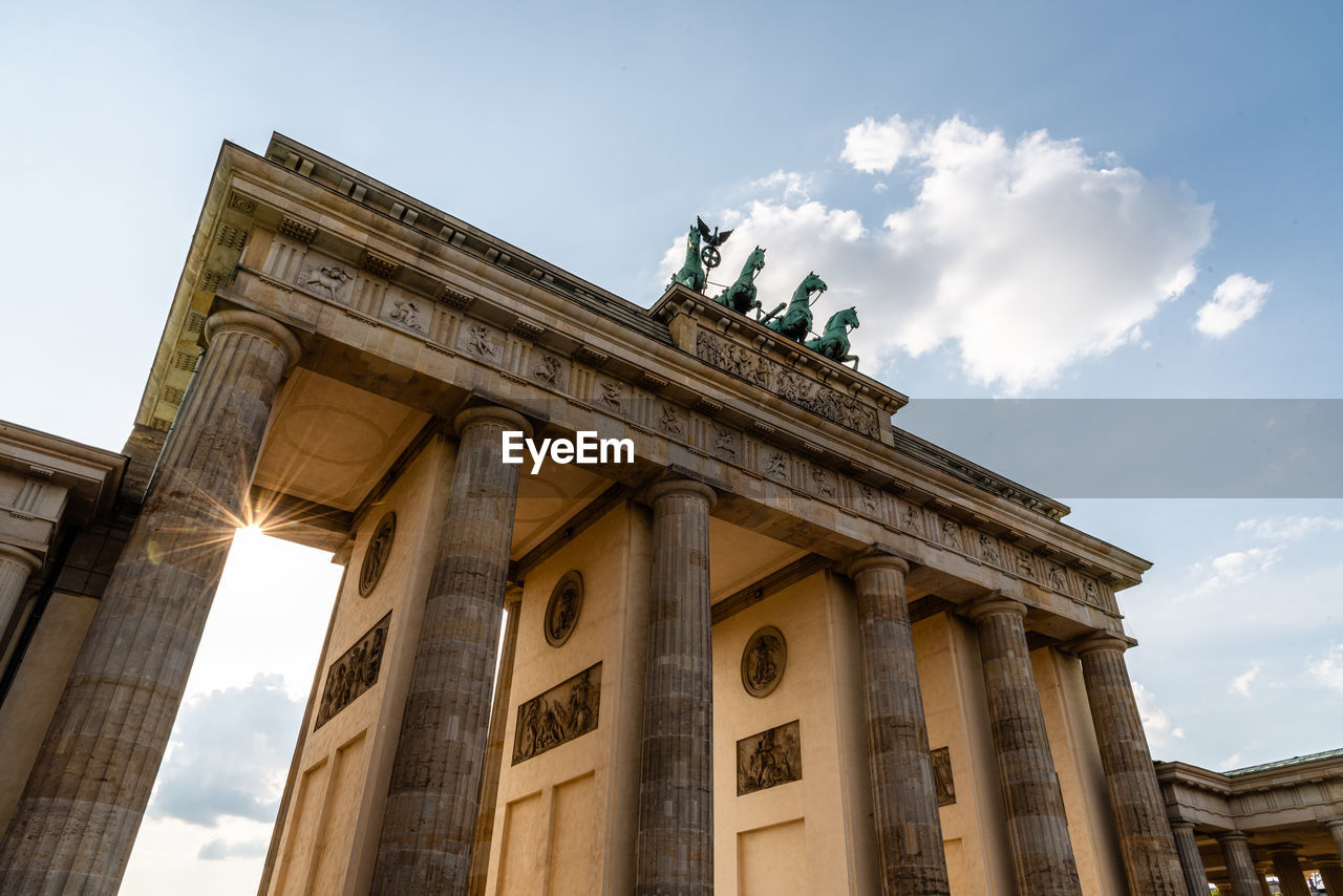 Low angle view of the brandenburg gate in berlin at evening, sun flare on background. germany