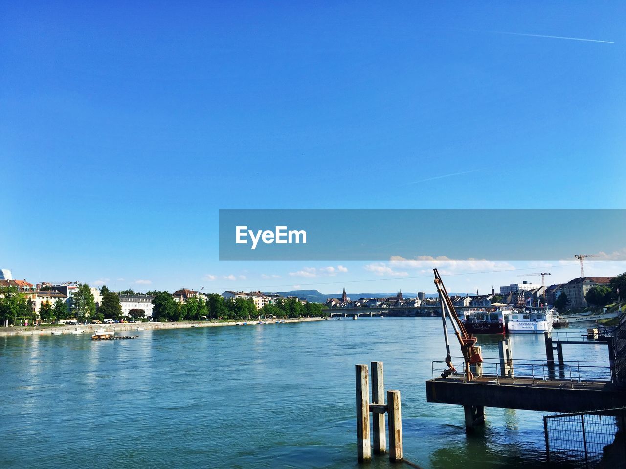 Scenic view of river by city against clear blue sky