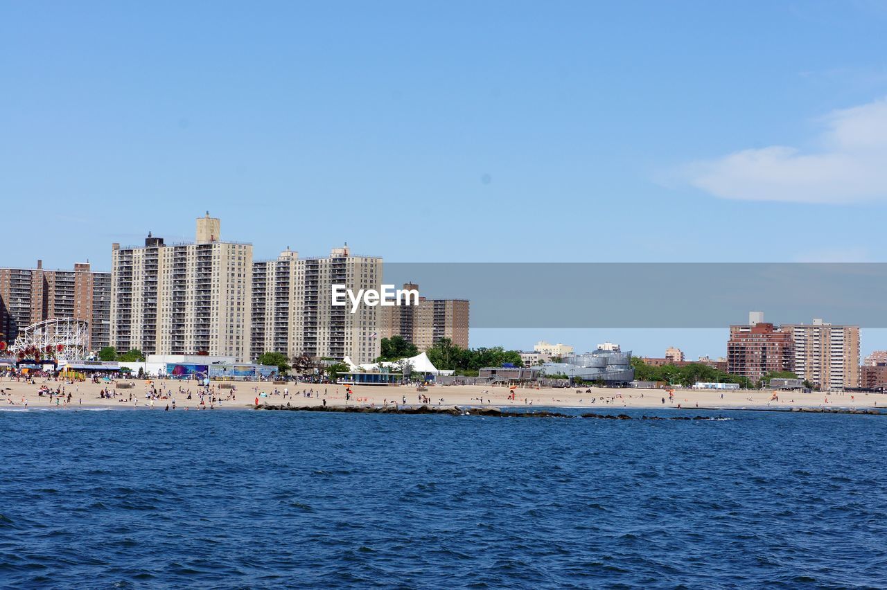 Sea by buildings against blue sky