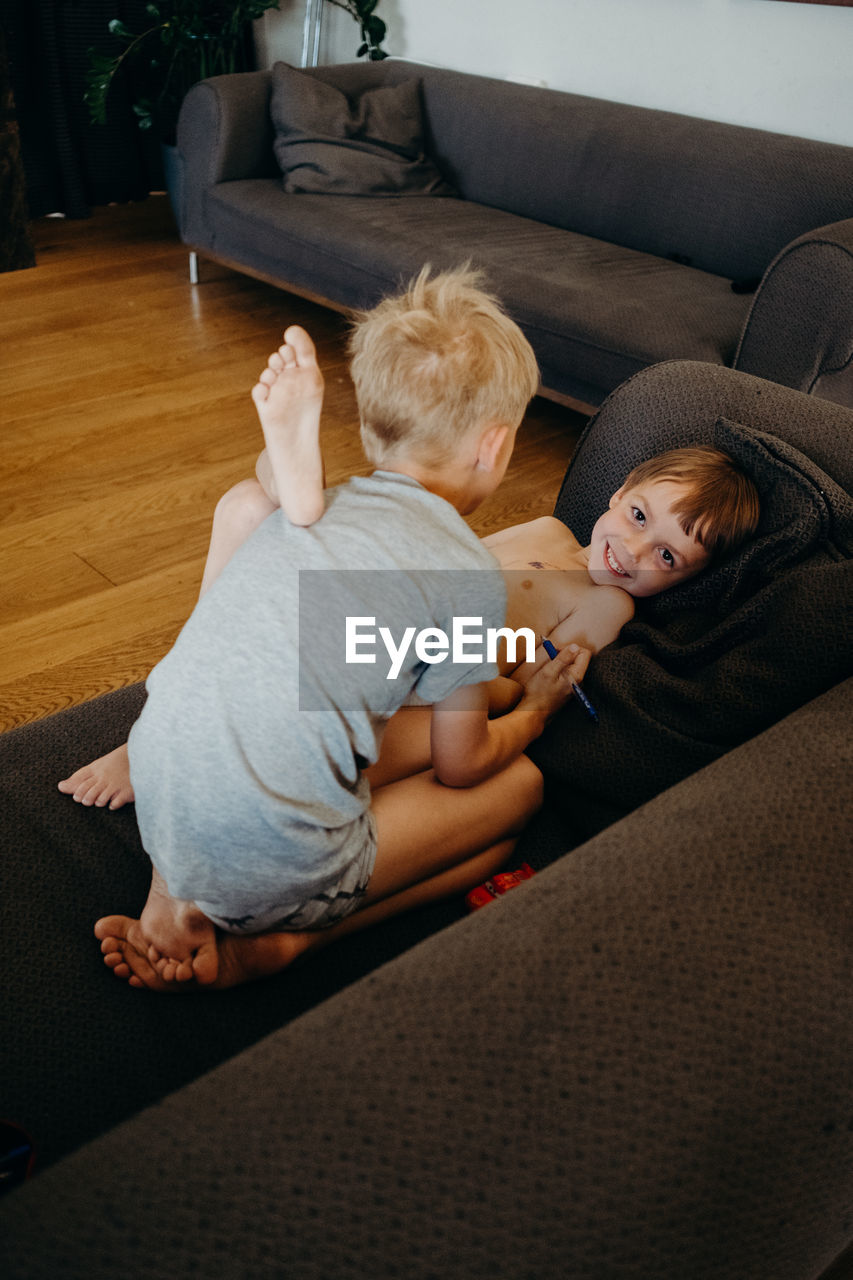 HIGH ANGLE VIEW OF CUTE BABY GIRL ON SOFA AT HOME