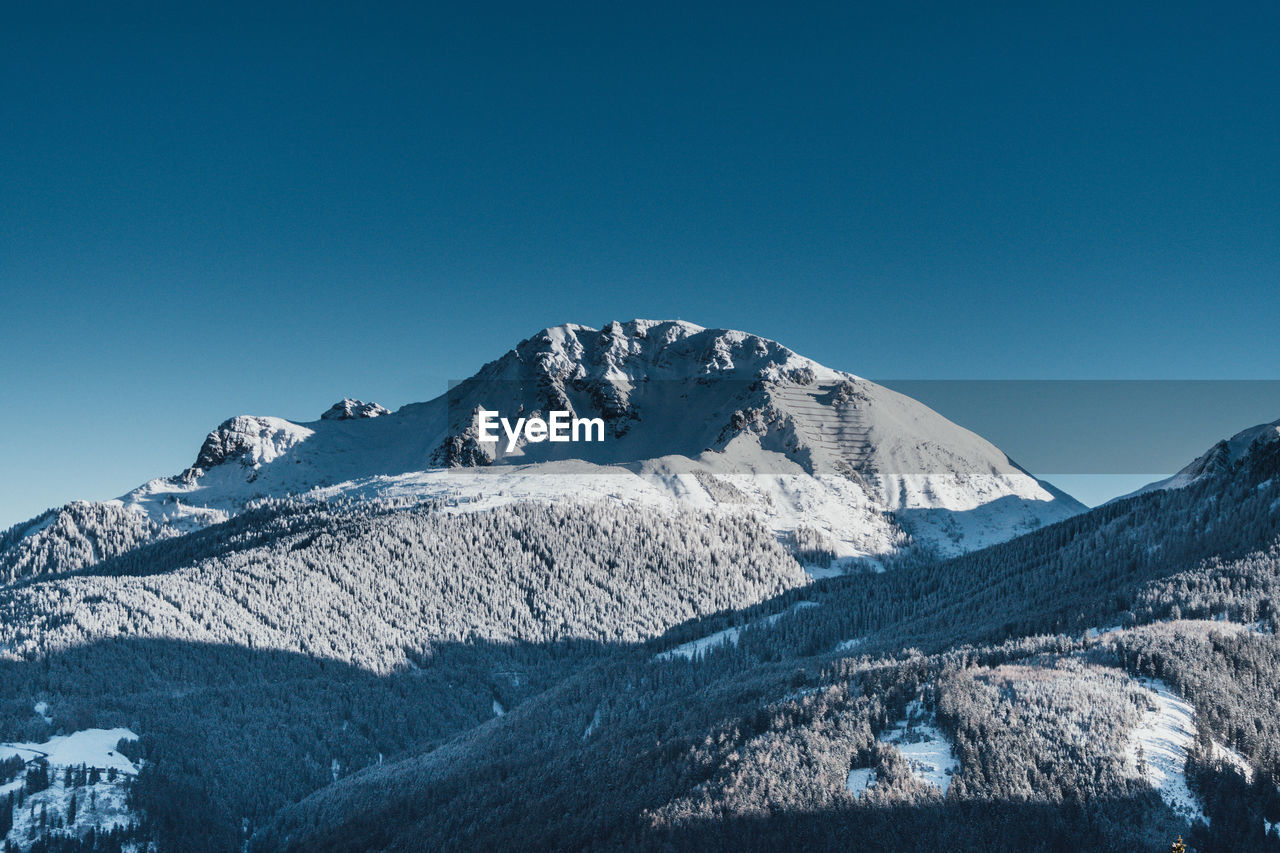 Scenic view of snowcapped mountains against clear blue sky