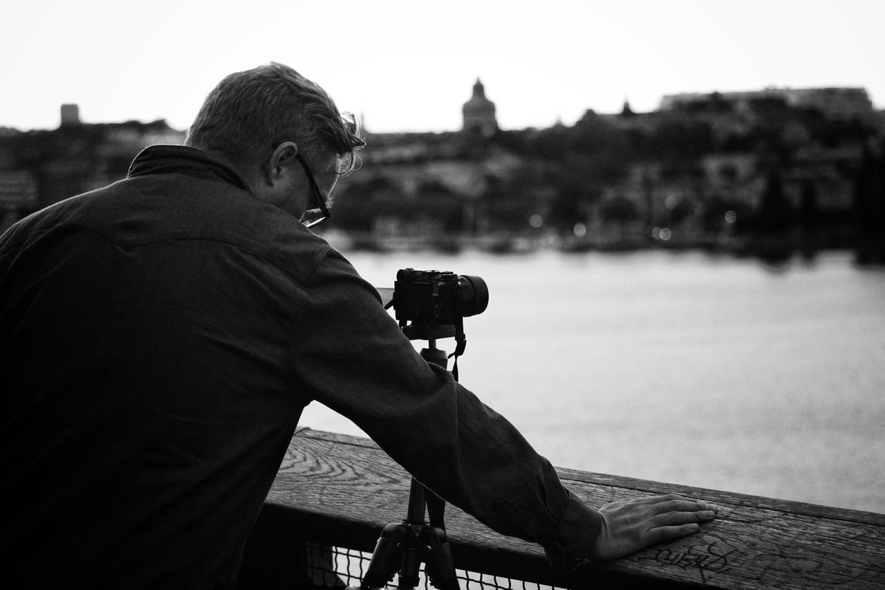 Rear view of man photographing against sky