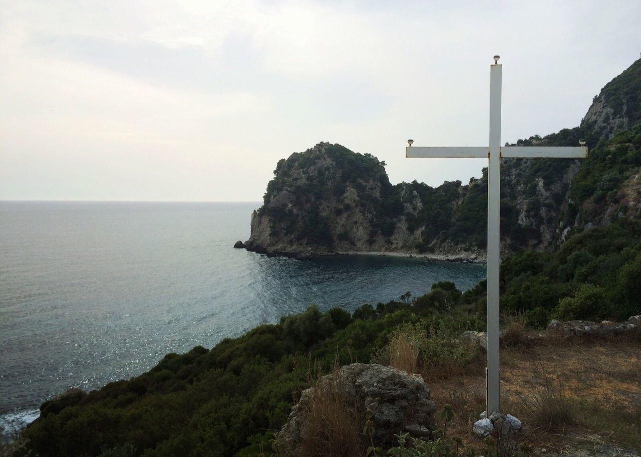 Metal cross in ermones beach against sky