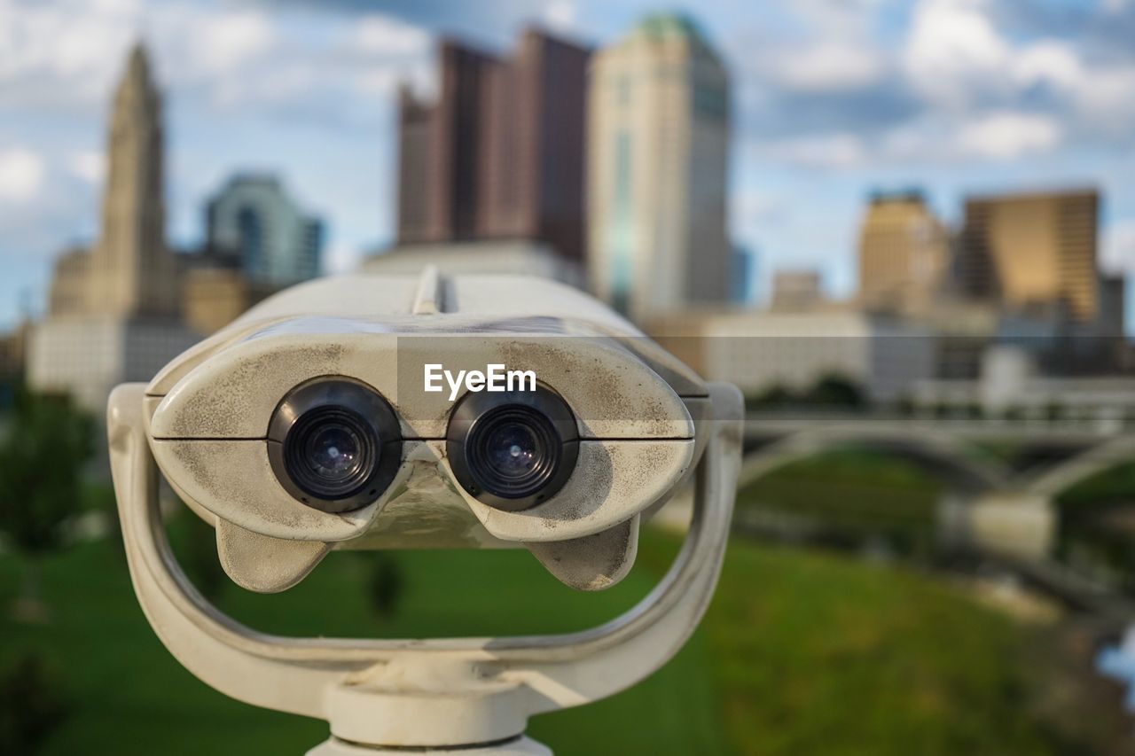 Close-up of coin-operated binoculars against cityscape