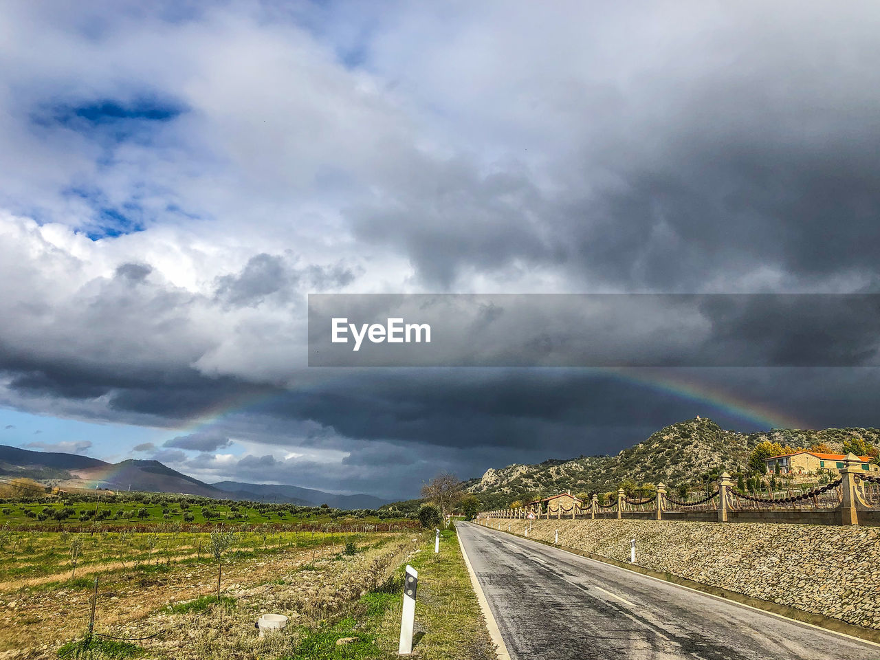 Empty road along landscape against cloudy sky