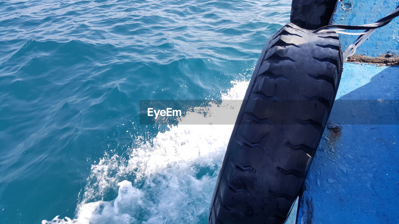 Cropped image of tire on boat in sea