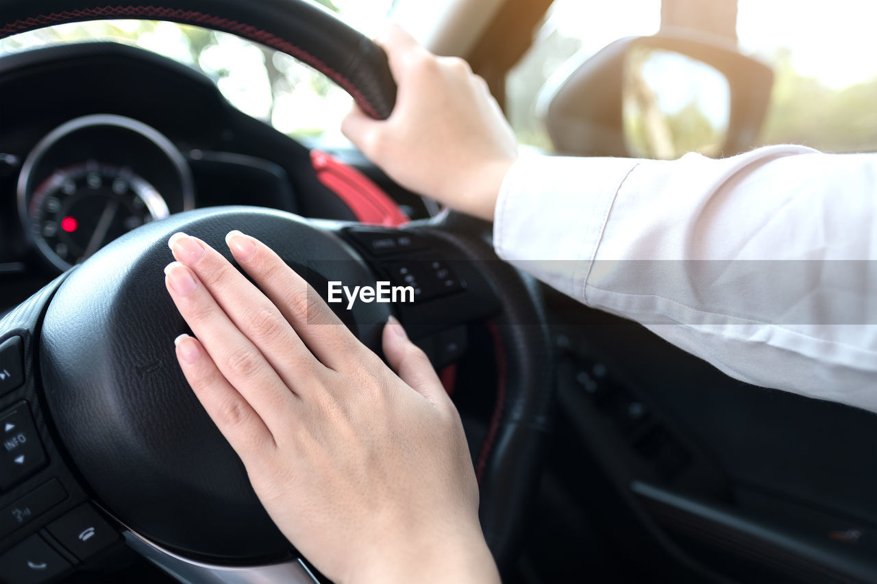 Cropped hands of woman driving car