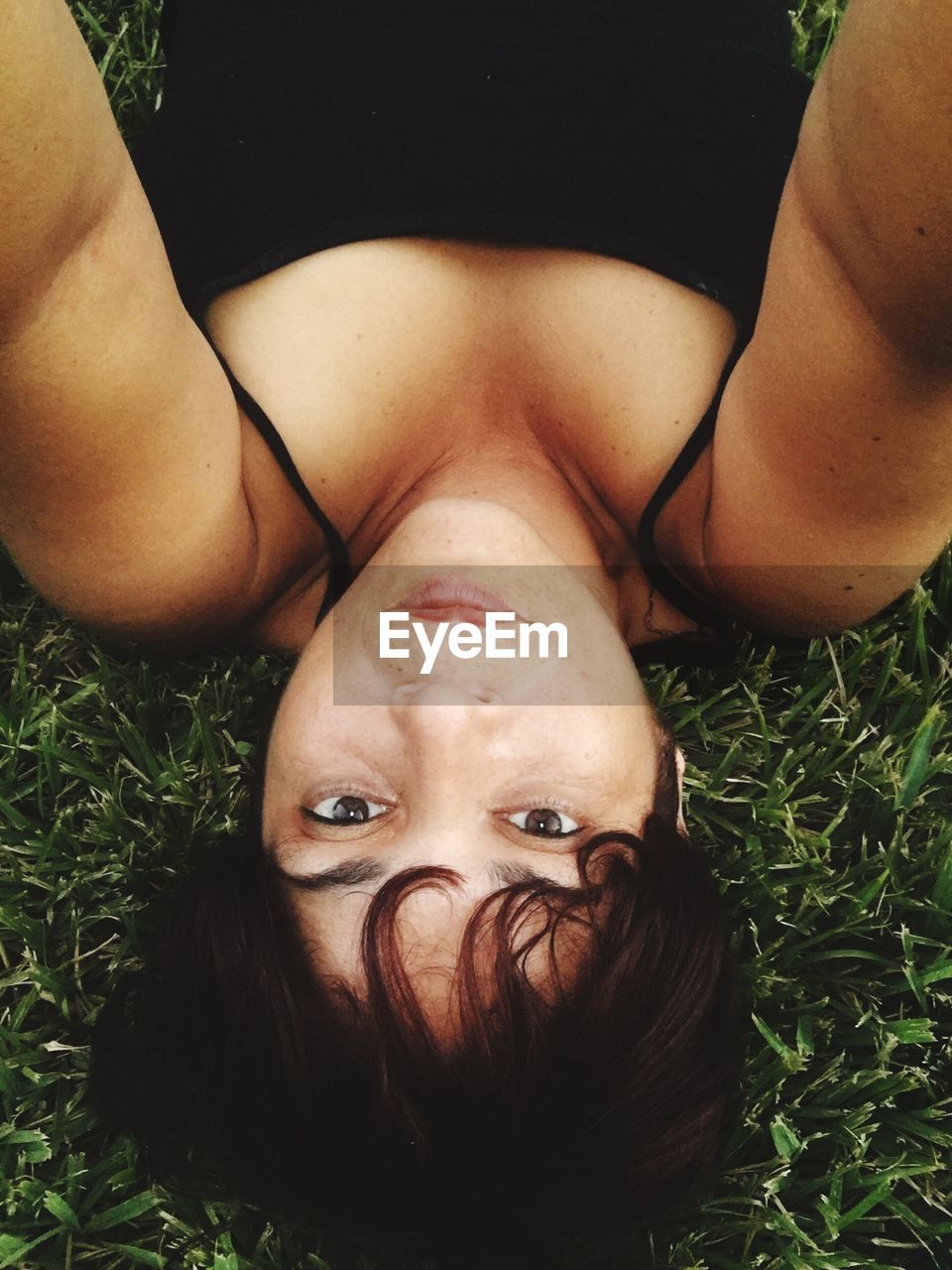 Portrait of woman lying down on grassy field