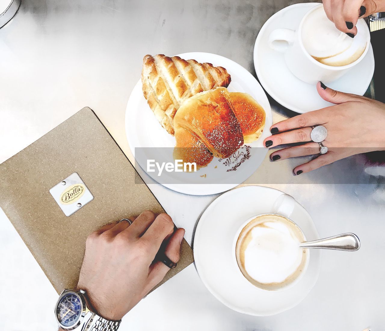 HIGH ANGLE VIEW OF WOMAN HOLDING COFFEE CUP AND CAKE