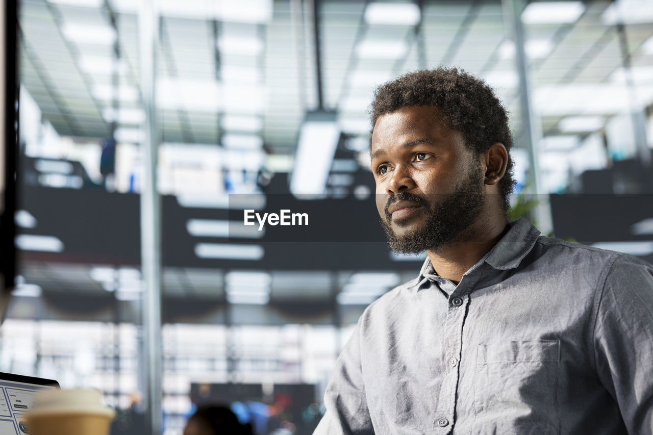 adult, one person, indoors, business, men, young adult, portrait, technology, business finance and industry, standing, beard, focus on foreground, occupation, businessman, working, looking, person, communication, facial hair, expertise, architecture, waist up, casual clothing, smiling, clothing, headshot, copy space, black hair, listening, office