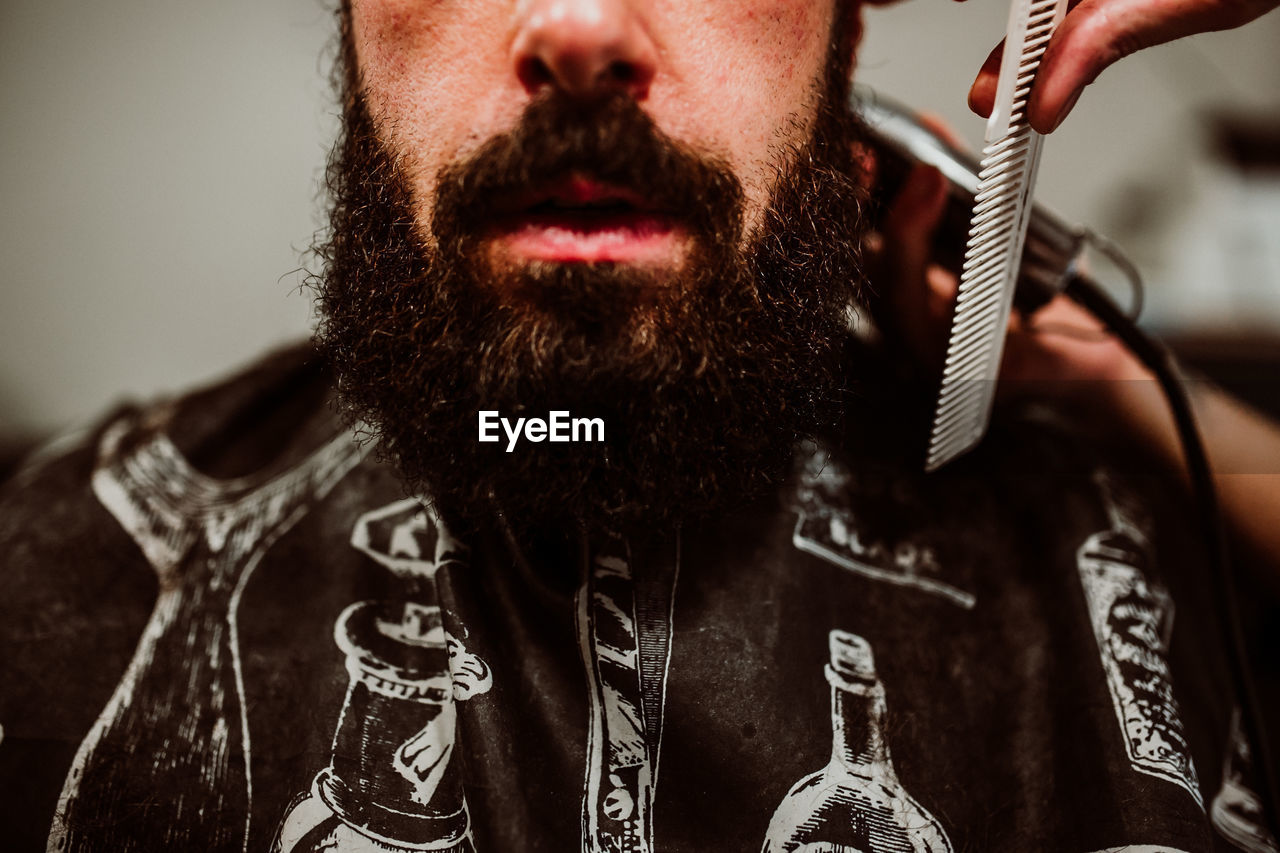 Cropped hands of barber grooming customer in salon