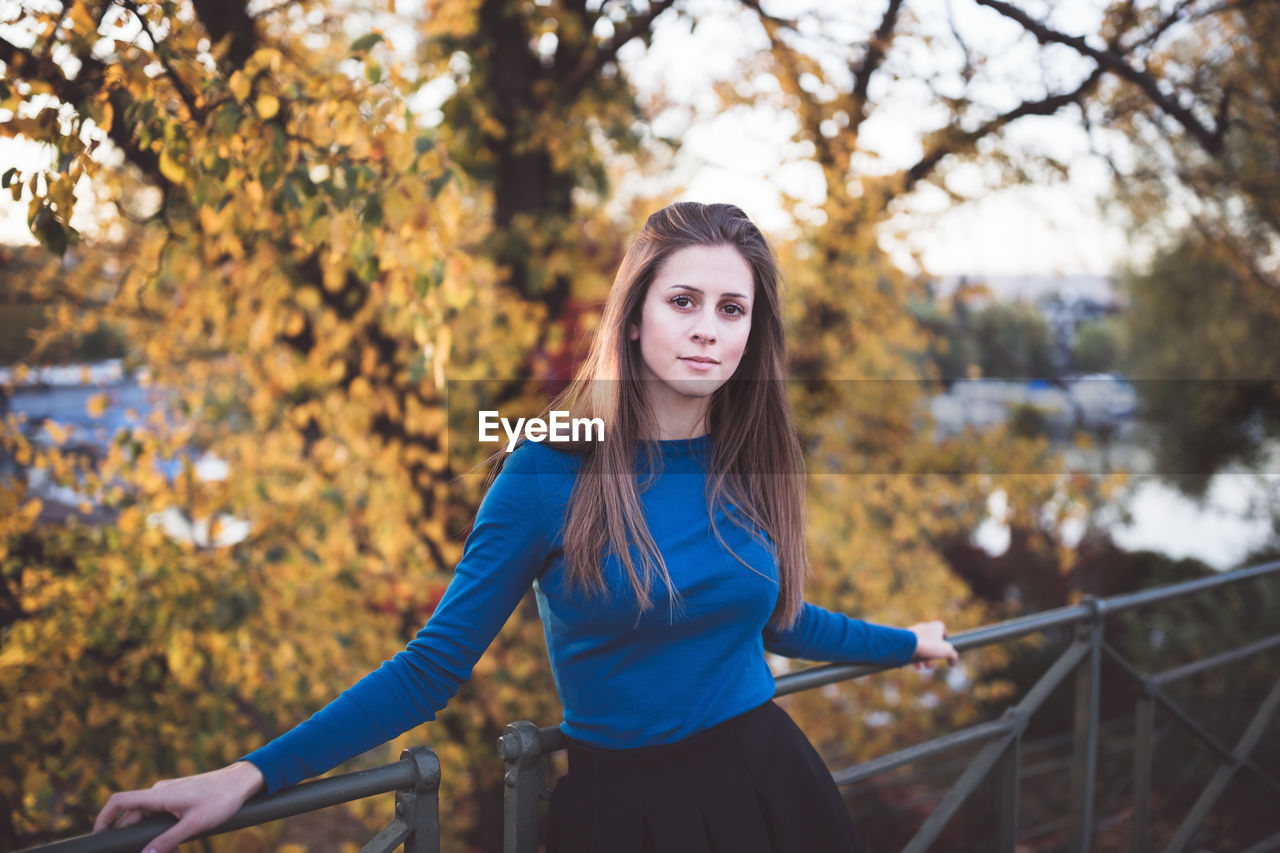 Girl in a blue long sleeve shirt and a skirt on a street. autumn time.