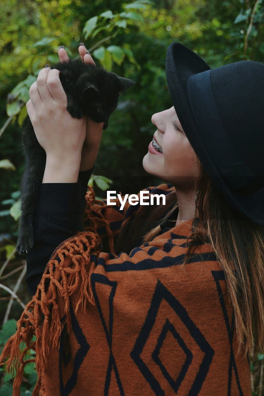 Woman in hat holding cat 