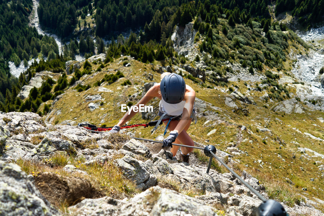 Full length of woman climbing rocks in a mountain at heini-holzer-klettersteig