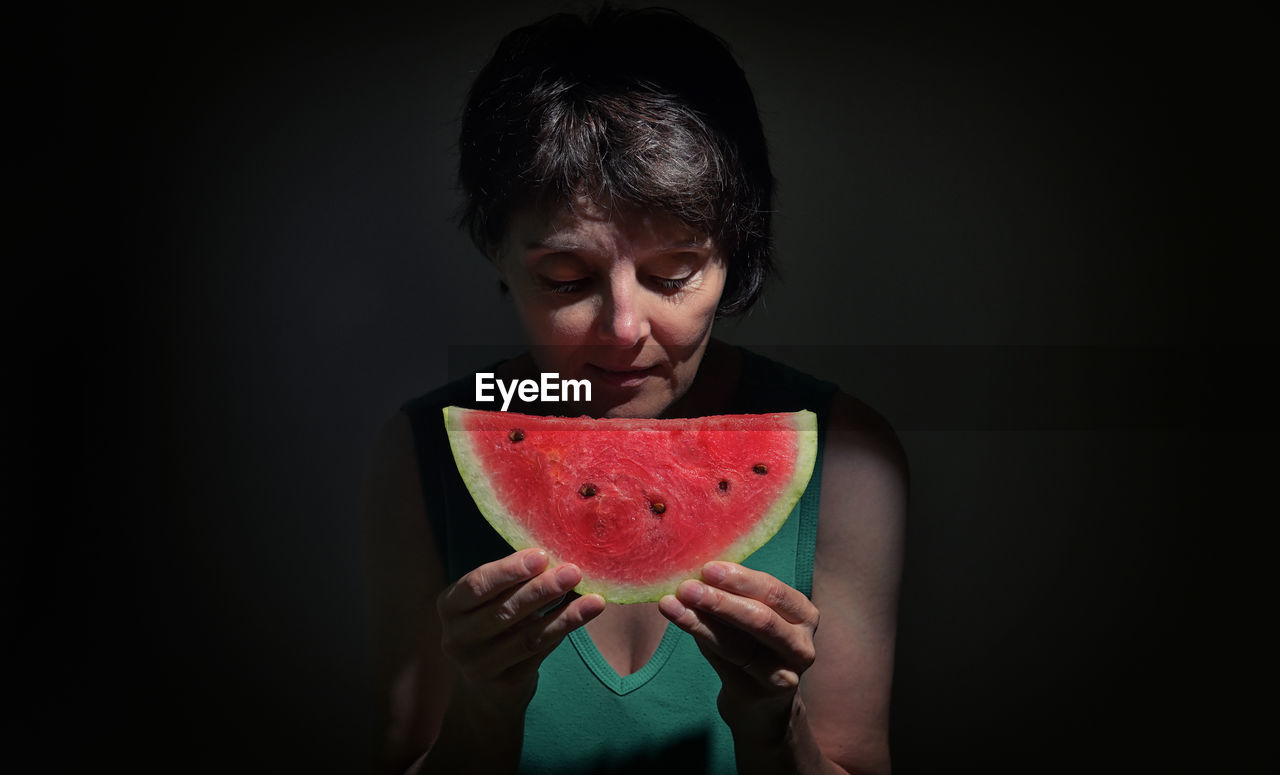 Woman holding slice of a red watermelon in studio