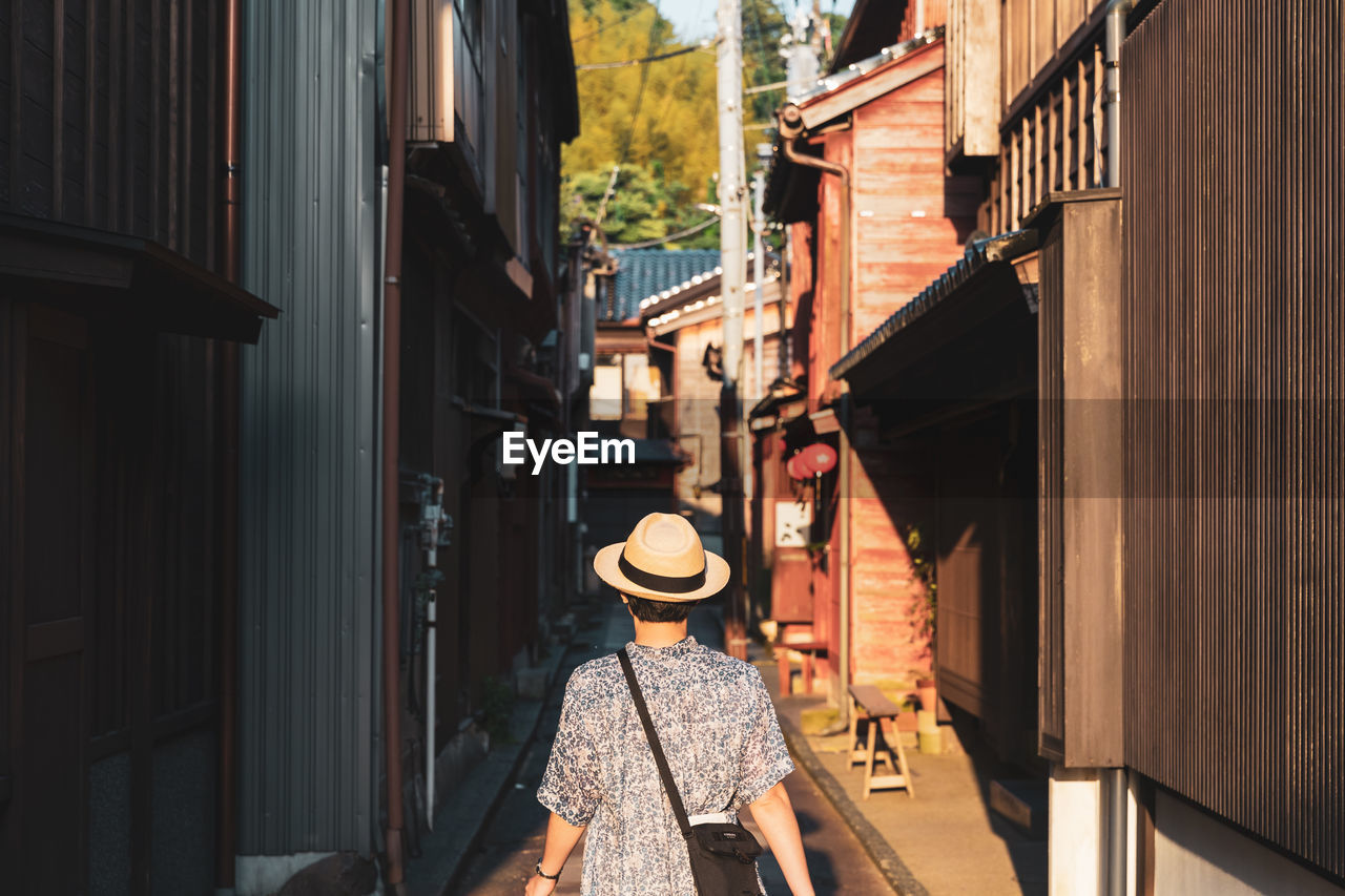 Rear view of man wearing hat walking at alley