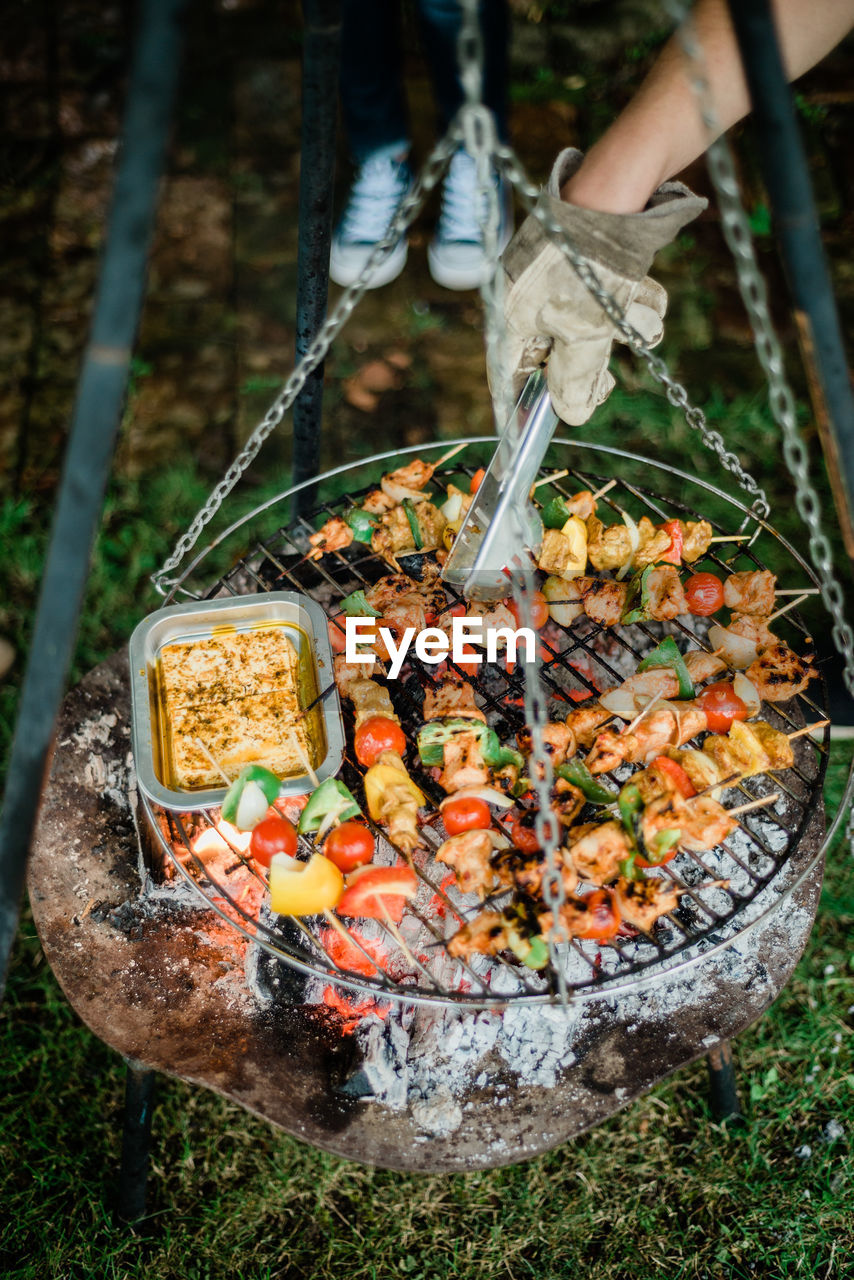 Cropped hand preparing food on barbecue grill