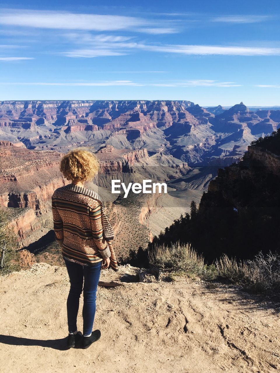 Rear view of woman looking at grand canyon against sky