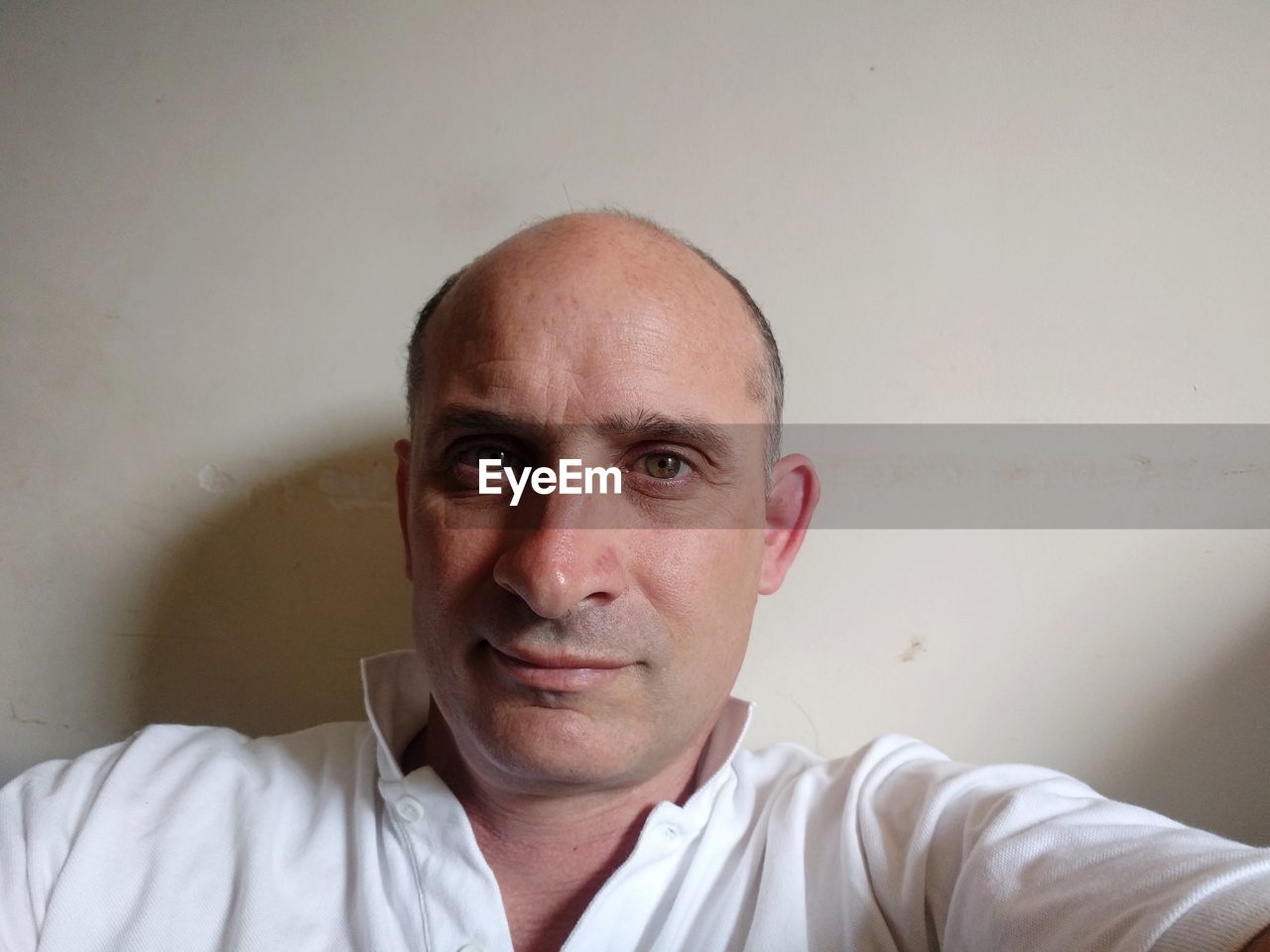 Close-up portrait of balding mature man against wall at home