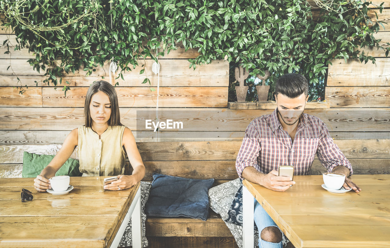 Couple using phones while having coffee in cafe