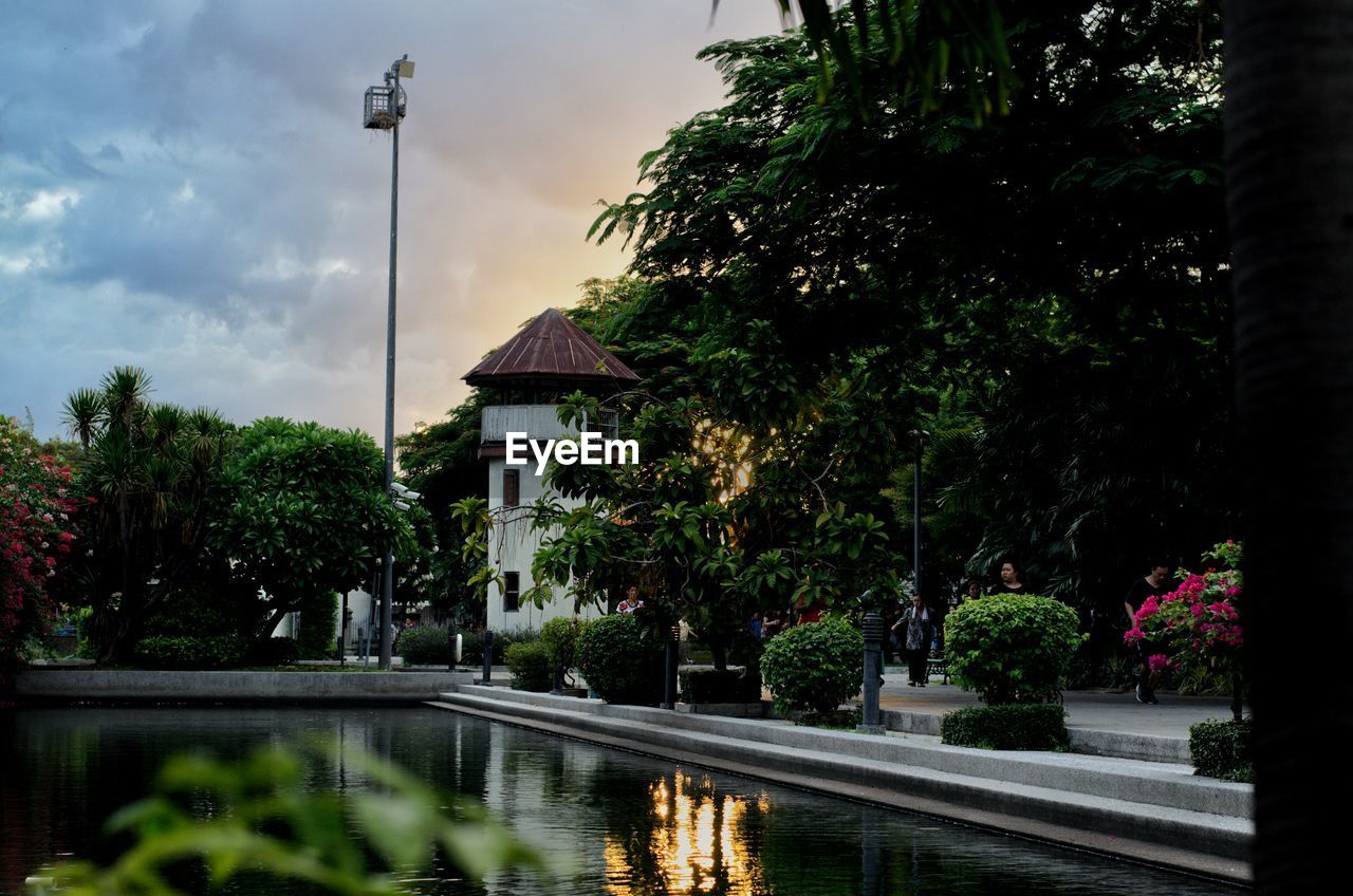 Street by lake and trees against sky