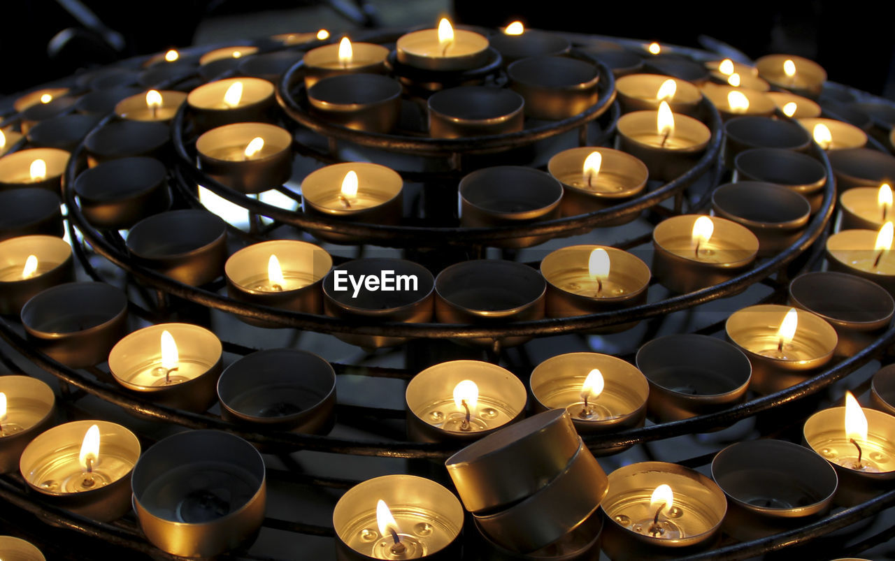 High angle view of illuminated tea lights on stand at night