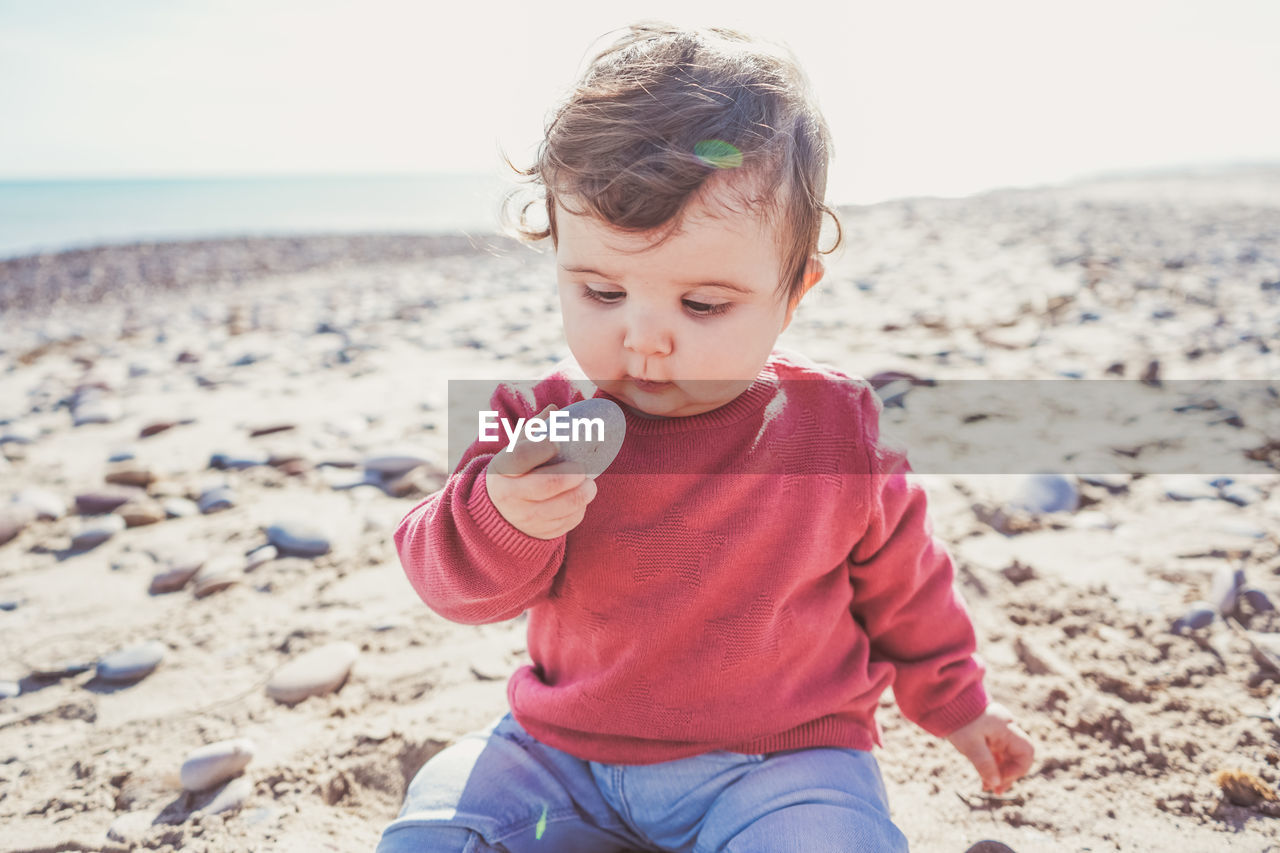 Cute girl holding pebble stone on beach