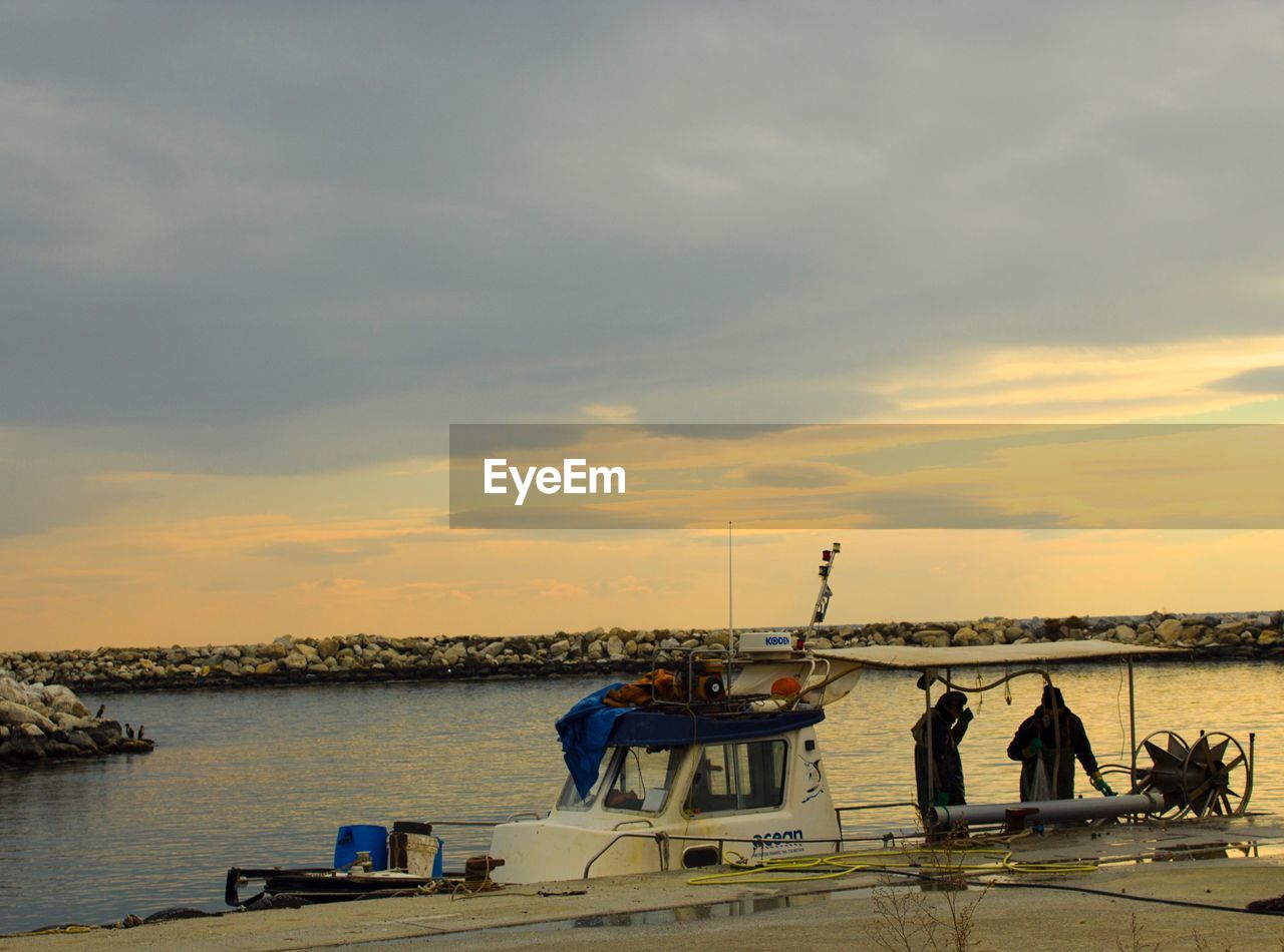 MEN STANDING ON SHORE AGAINST SKY