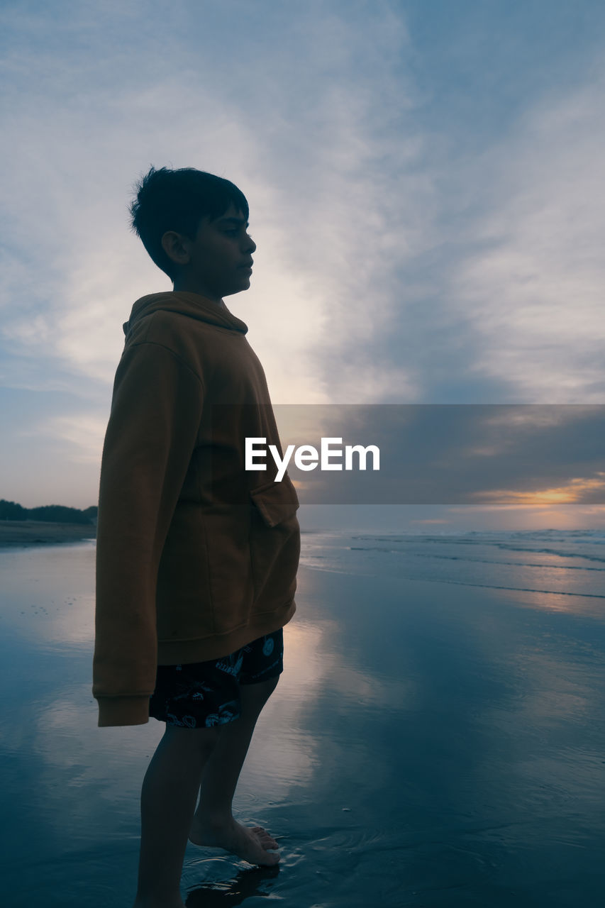 rear view of man standing against sky during sunset