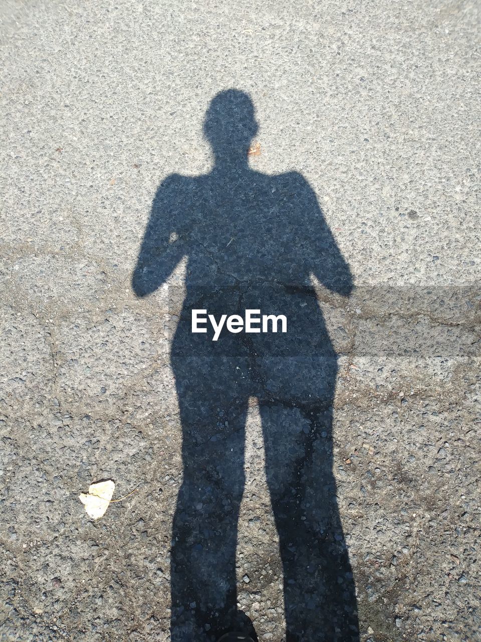 SHADOW OF MAN STANDING ON GROUND