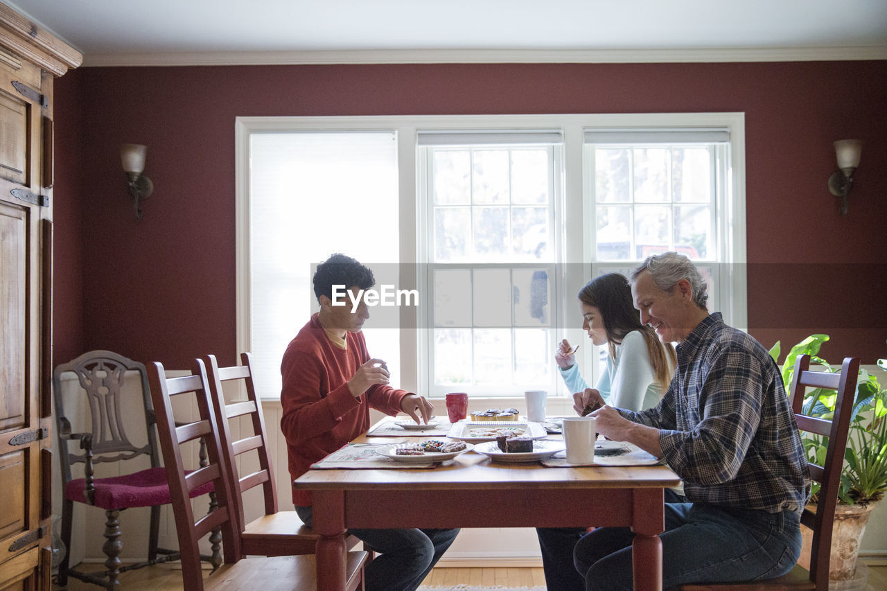 Happy family eating breakfast at table in home