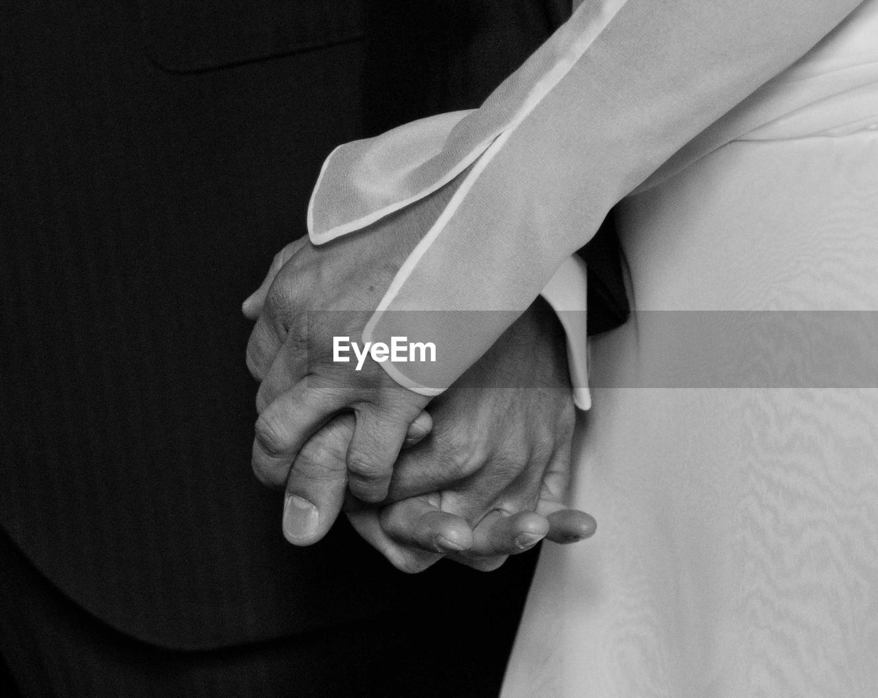 Close-up of couple holding hands at wedding
