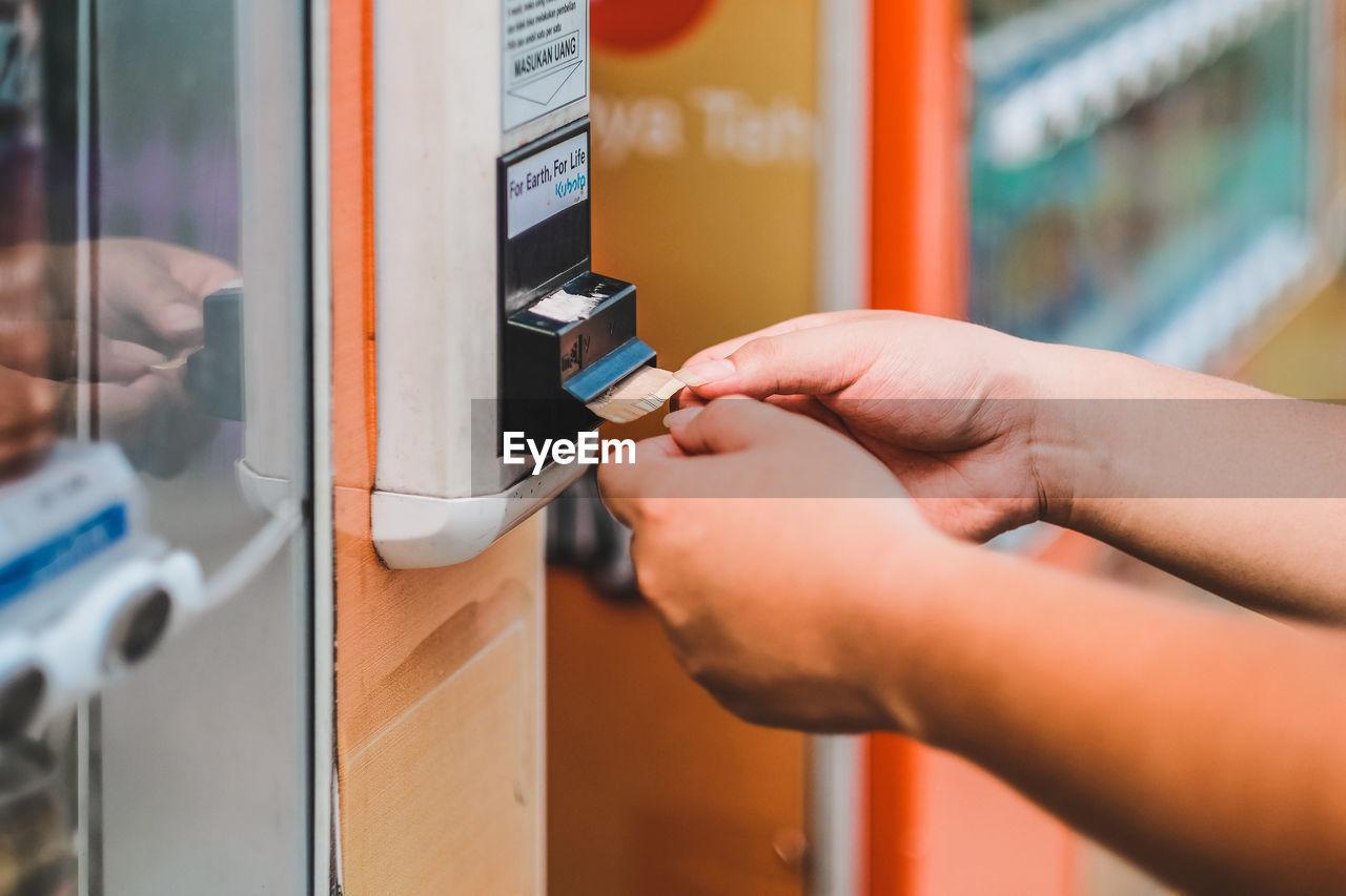 Close-up of hands collecting paper currency dispensing from machine