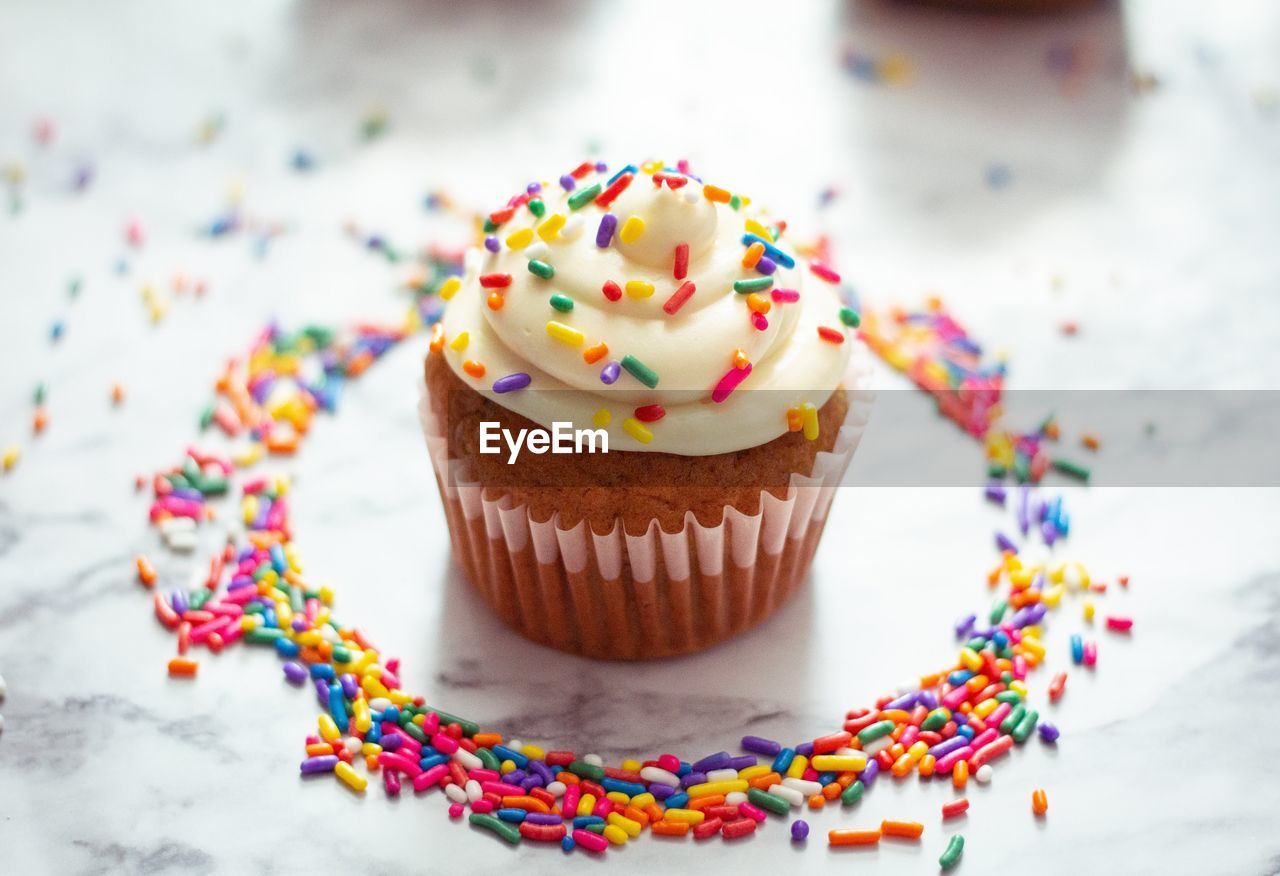 High angle view of cupcake and sprinkles on table