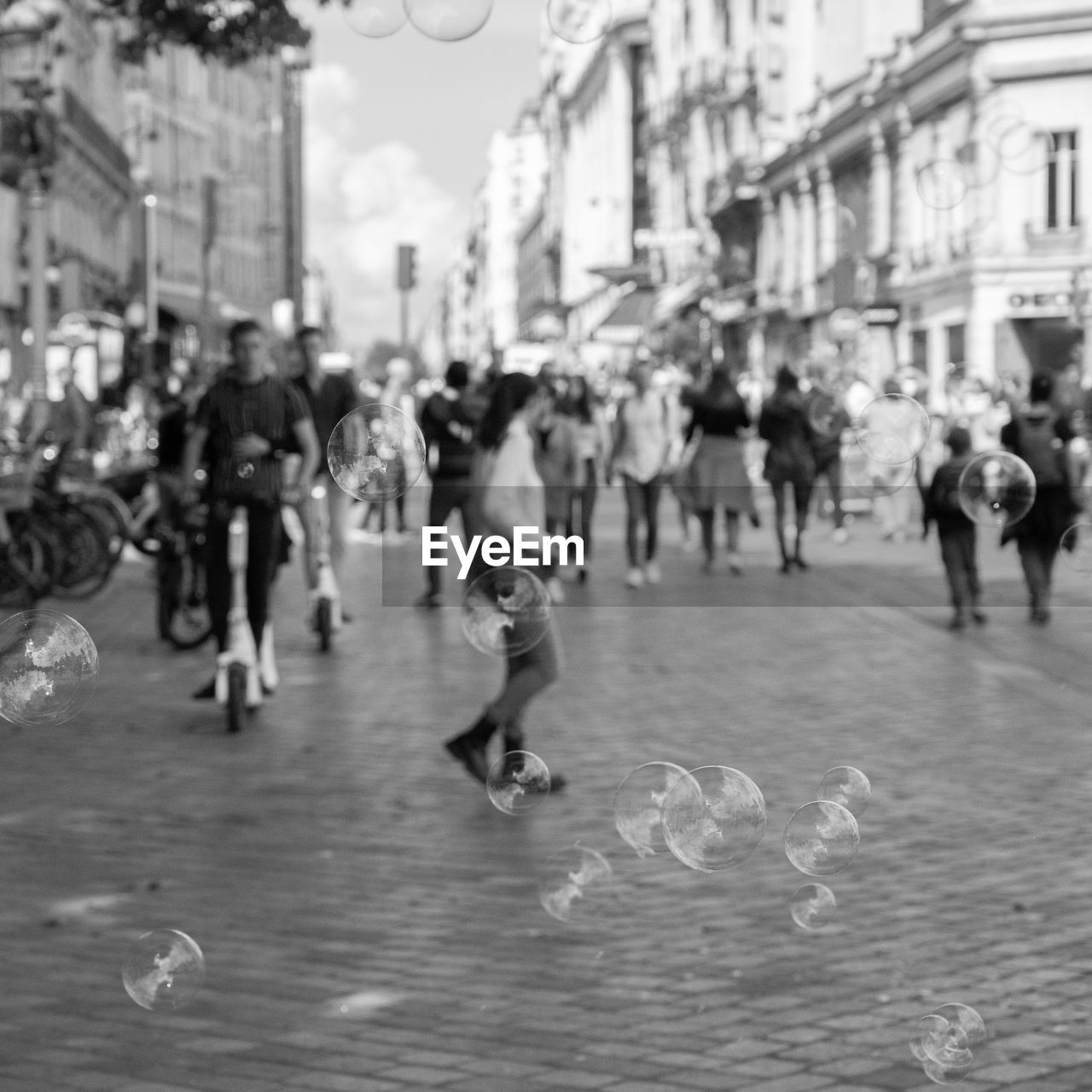 city, architecture, large group of people, crowd, group of people, road, street, black and white, building exterior, built structure, city life, men, motion, women, day, monochrome photography, monochrome, walking, adult, city street, lifestyles, outdoors, rain, nature, infrastructure