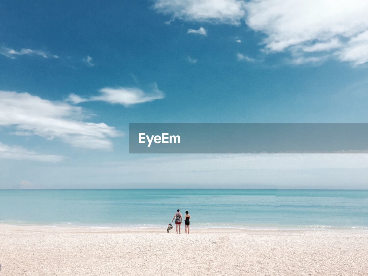 Two people standing on idyllic sandy beach