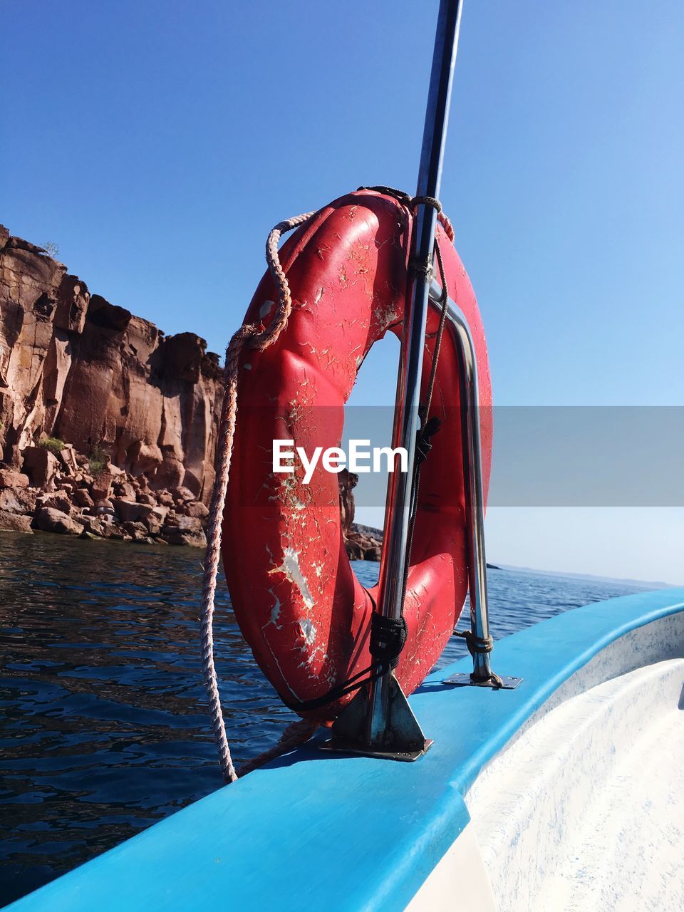 Red boat in sea against clear blue sky