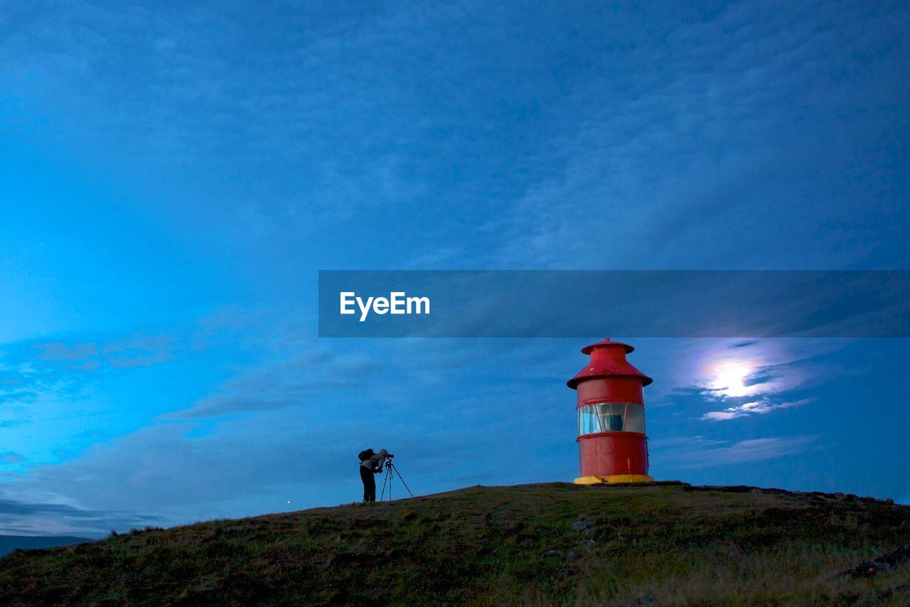 Man standing on field next to lighthouse