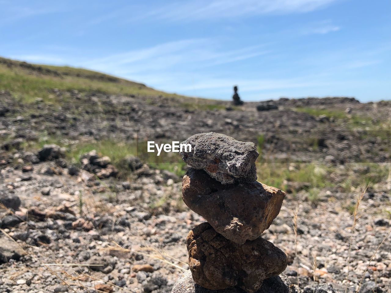 Close-up of stacked rock on field against sky