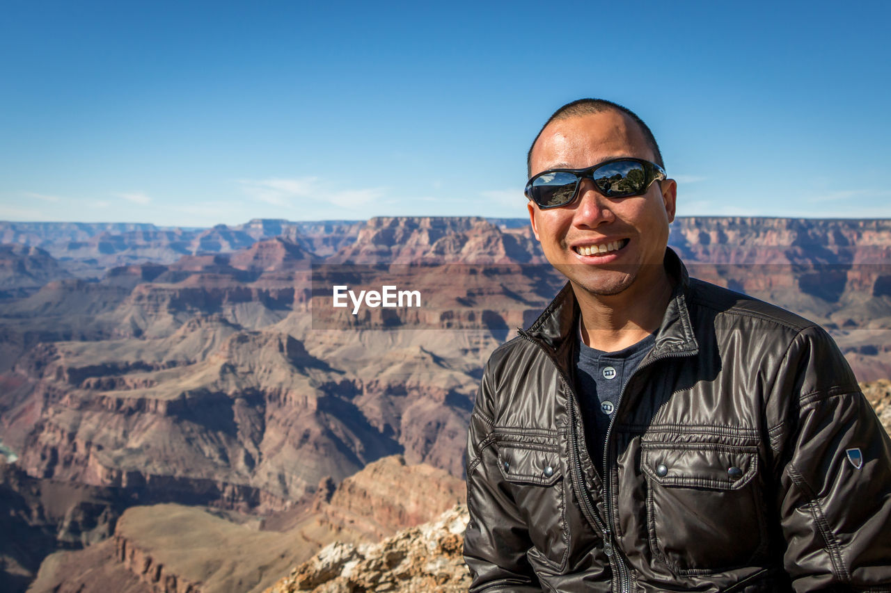 Portrait of smiling man wearing sunglasses on desert against rock formations