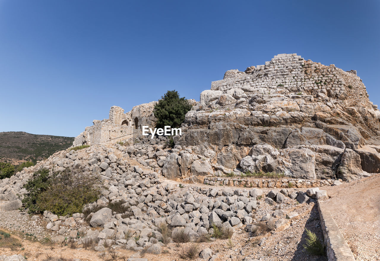 LOW ANGLE VIEW OF ROCKS ON MOUNTAIN AGAINST SKY