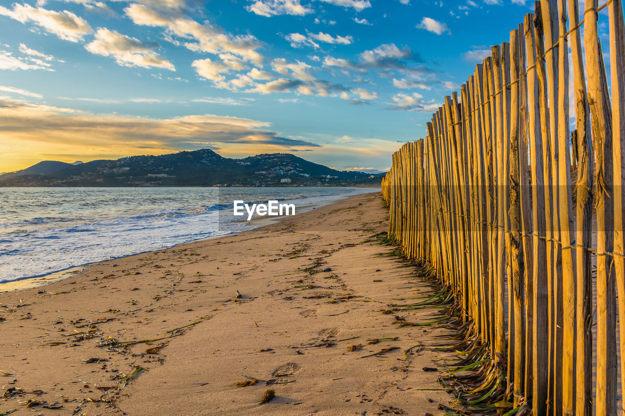 Scenic view of wooden fence at beach against dramatic sunset sky near saint tropez south of france