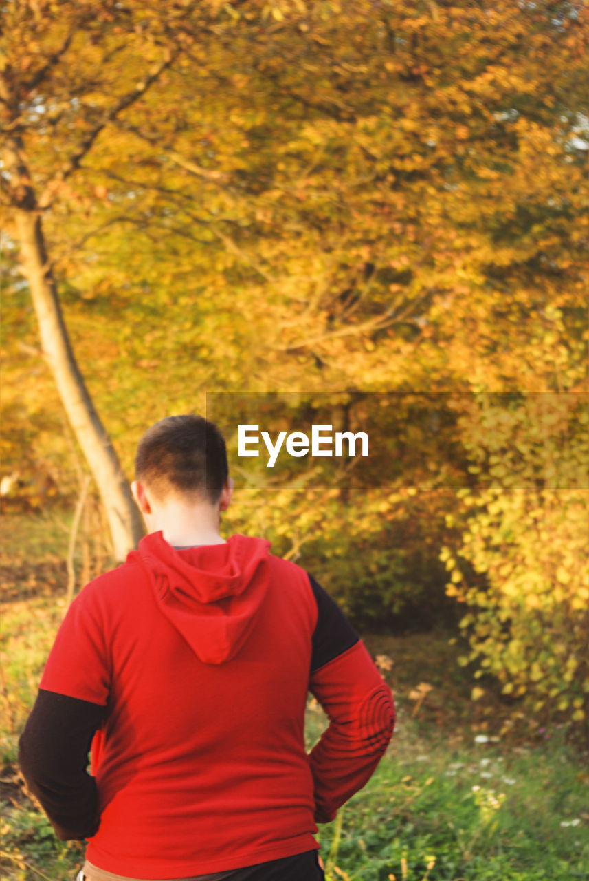 REAR VIEW OF MAN STANDING AGAINST ORANGE SKY