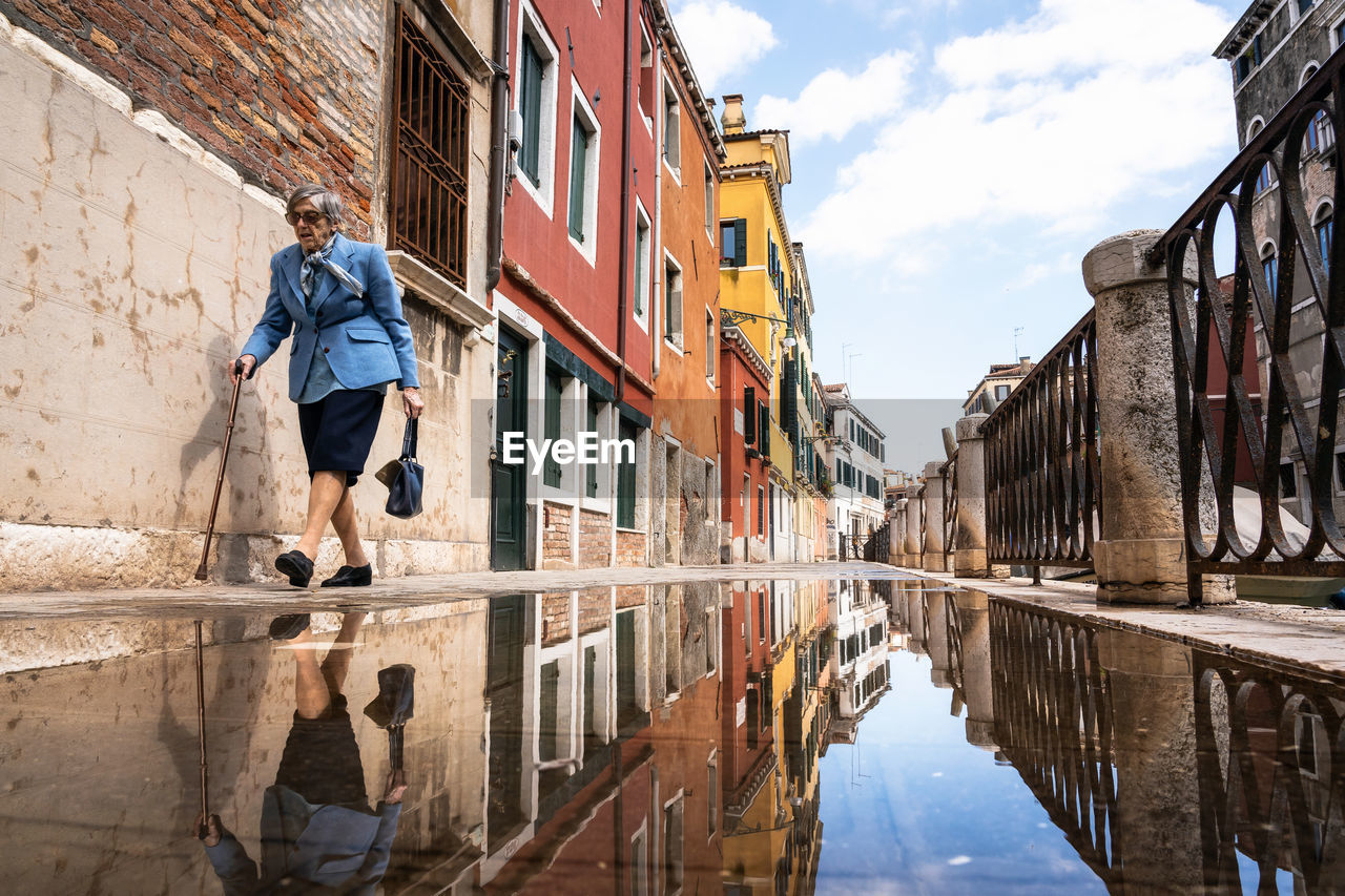 REFLECTION OF MAN AND BUILDINGS ON CANAL