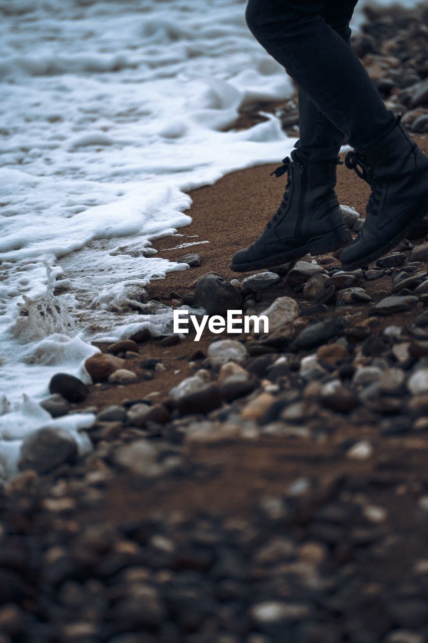 Low section of man standing on beach