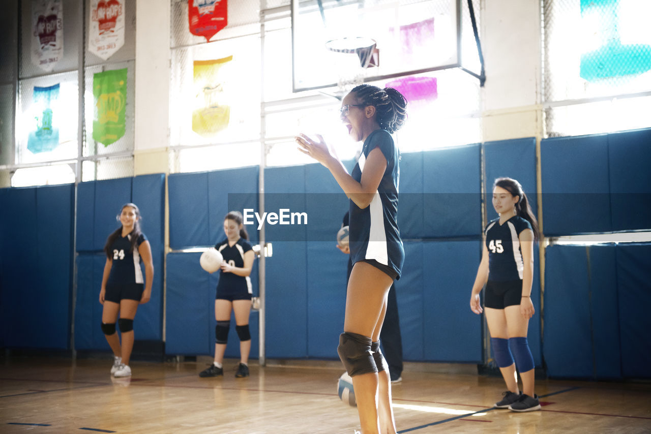 Teenage girls playing at indoor volleyball court